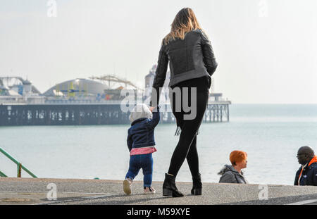 Brighton, UK. 21 Feb, 2018. Kleinkind genießt einen Spaziergang entlang der Küste von Brighton mit ihrer Mutter auf einem herrlichen sonnigen Tag: Simon Dack/Alamy leben Nachrichten Stockfoto