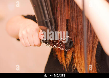 Frau ihr Haar trocknen mit Pinsel und Haartrockner Stockfoto