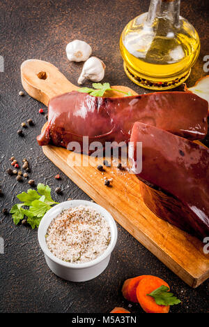 Rohes Rindfleisch Leber mit Gewürzen, Kräutern und Gemüse, dunkle rusty Tabelle kopieren Raum Stockfoto