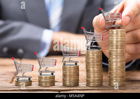 Mittelteil der Geschäftsmann Inverkehrbringen Warenkorb auf Gestapelte Münzen in aufsteigender Reihenfolge Stockfoto