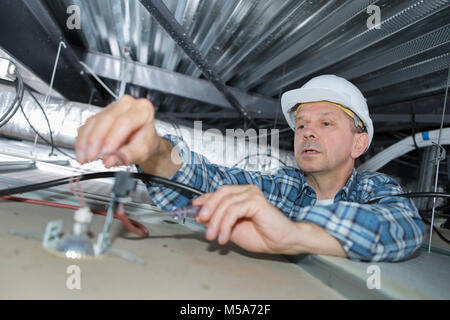 Elektromeister bei der Arbeit in der Dachfläche Stockfoto