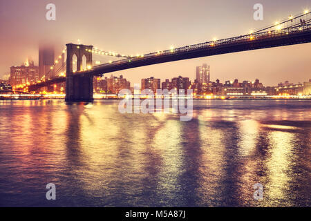 Brooklyn Bridge und Manhattan an einem nebligen Nacht, Farbe getonte Bild, New York City, USA. Stockfoto