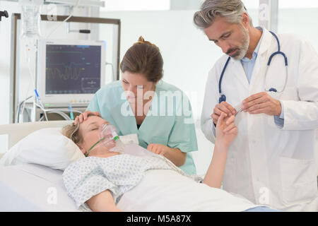 Ärzte setzen eine Sauerstoffmaske auf Patient im Krankenhaus Stockfoto