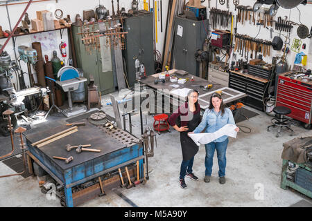 Hohe Betrachtungswinkel von zwei Frauen, die in der Metallwerkstatt, die den technischen Entwurf. Stockfoto