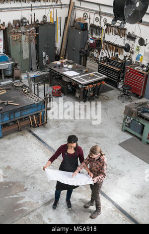 Hohe Betrachtungswinkel von zwei Frauen, die in der Metallwerkstatt, die den technischen Entwurf. Stockfoto