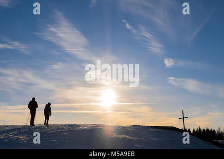 Vater und Sohn Wandern auf verschneiten Berg Schoeckl zum Gipfelkreuz mit schönen Sonnenuntergang in Österreich Stockfoto