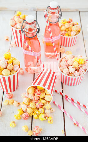 Bunte Popcorn in gestreifte Tassen und Limonade in vintage Flaschen Stockfoto