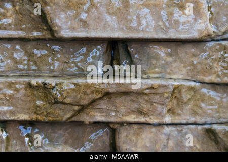Steinmauer mit Wasser nach unten läuft. Stockfoto