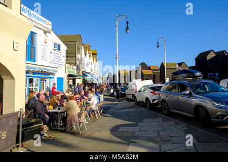 Hastings, Leute, die an einem sonnigen, warmen Februar-Tag draußen essen, Rock-A-Nore Road, an den Netzhütten am Meer, East Sussex, Großbritannien Stockfoto