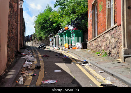 Müll und Abfall littering kleine Gasse mit überquellenden Mülleimer von Abfällen, Großbritannien Stockfoto