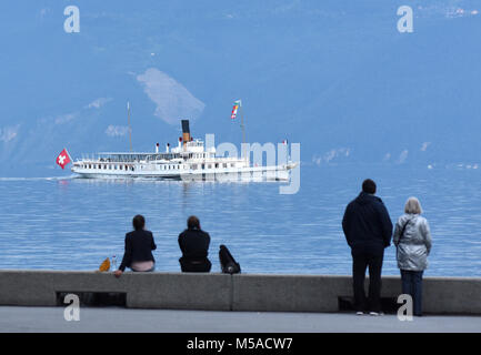 Die Menschen am Ufer am Genfer See in Lausanne mit Bootsfahrt auf dem Hintergrund. Stockfoto