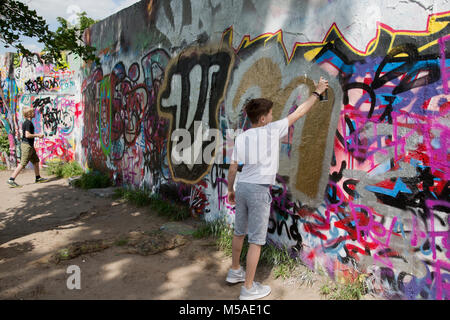 Berlin, Deutschland, 21. Mai - 2017: Zwei Jungen Farbe spritzen auf bunten Graffiti Wandbild Kunstwerk an der ehemaligen Berliner Mauer am Mauerpark an einem sonnigen Tag in Stockfoto