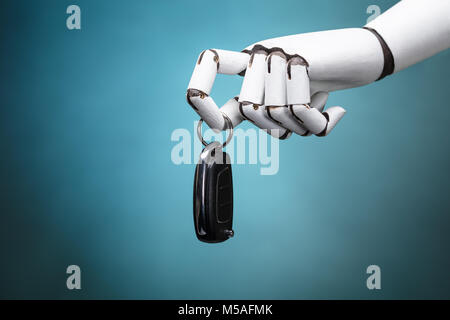 Nahaufnahme eines Roboters Holding Autoschlüssel auf Türkisfarbenem Hintergrund Stockfoto