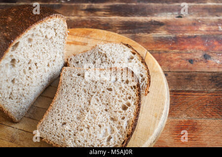 Frisch gebackene geschnittenes Brot auf einer Küche aus Holz Schneidebrett auf alten Holz- rustikalen Tisch aus Brettern. Stockfoto