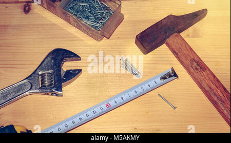 Hammer Nägel Schraubenschlüssel und Meter auf einen Stall in Hellbraun Holz platziert Stockfoto