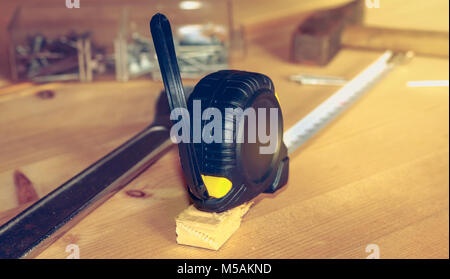 Hammer Nägel Schraubenschlüssel und Meter auf einen Stall in Hellbraun Holz platziert Stockfoto