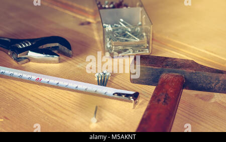 Hammer Nägel Schraubenschlüssel und Meter auf einen Stall in Hellbraun Holz platziert Stockfoto