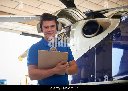 Portrait der männlichen Aero Ingenieur mit Zwischenablage Durchführung auf Helikopter im Hangar prüfen Stockfoto