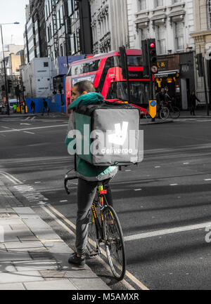 Deliveroo (online Food Delivery Company), Mountainbike/Fahrrad-Fahrer, die mit einem Auftrag in einem Beutel/Container auf dem Rücken, im Zentrum von London, England, UK. Stockfoto