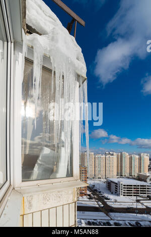 Große Eiszapfen hängen auf dem Balkon eines Hauses in der Stadt Stockfoto