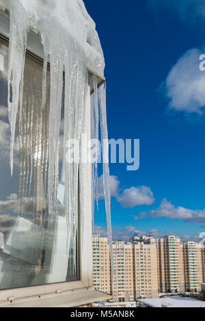 Große Eiszapfen hängen auf dem Balkon eines Hauses in der Stadt Stockfoto