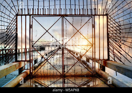 Alte Metal und rostige Tür am Meer Brücke Foto im Sonnenuntergang die gedämpfte Beleuchtung. Stockfoto
