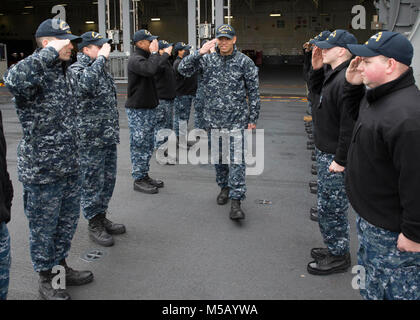 NORFOLK, Virginia (Feb. 14, 2018) - Fachkraft für Lagerlogistik Seaman Nigel Marcos, aus San Diego, auf USS Gerald R. Ford's (CVN 78) Versorgung der Abteilung zugewiesen, kehrt die Salute von Ford Segler, als er den Befehl fährt. (U.S. Marine Stockfoto