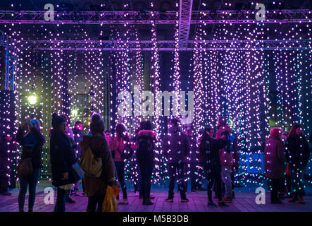 Edinburgh, Schottland, Vereinigtes Königreich, 21. Februar 2018. Night Light Display im Stadtzentrum von Edinburgh "Edinburgh Lumen', erstellt und von dem NL Produktionen für Stadt Edinburgh Rat produziert. Es ist so konzipiert, dass Sie im Winter am Abend zu erhellen. An der Unterseite der Damm ist "Ocean of Light", bis der suspendierten Farbe ändern Lichter, die die Besucher gehen kann durch Musik begleitet. Eine Masse von Menschen stehen unter den bunten Lichtern und genießen die Musik und Ruhe und Fotos Stockfoto