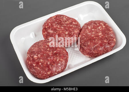 Fach mit rohem Rindfleisch Burger auf grauem Hintergrund Stockfoto