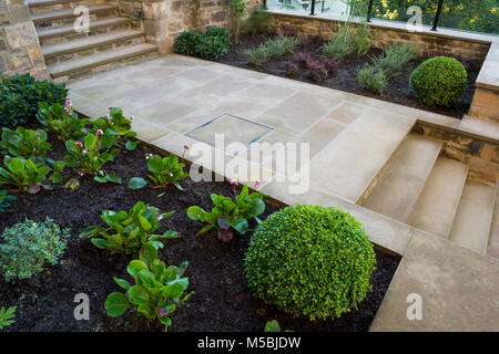 Kleine Ecke des schönen, gepflegten, privaten Garten mit zeitgenössischem Design, gepflasterter Weg & Schritte, Sträucher und Pflanzen - Yorkshire, England, UK. Stockfoto