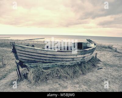 Abgebrochene Fischerboot auf Bank von Meer. Morgen stille Bucht innerhalb windstill. Dramatische und malerische Szene. Dark Sky in Wasser spiegel Stockfoto