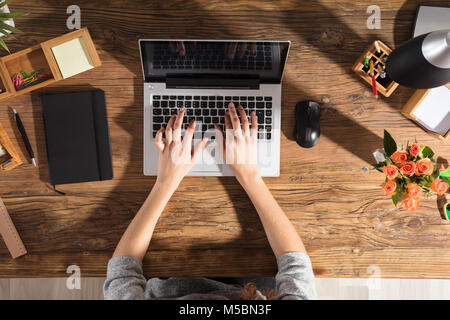 Nahaufnahme einer Person mittels Laptop auf Büro Schreibtisch aus Holz Stockfoto