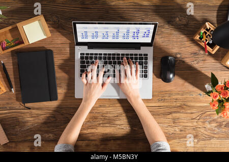 Erhöhte Ansicht einer Person mit Laptop mit dem Kalender auf dem Bildschirm am Arbeitsplatz Stockfoto