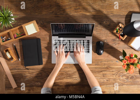 Nahaufnahme einer Person mittels Laptop auf Büro Schreibtisch aus Holz Stockfoto