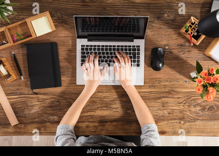 Nahaufnahme einer Person mittels Laptop auf Büro Schreibtisch aus Holz Stockfoto