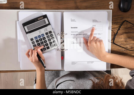 Nahaufnahme einer Businessperson Berechnung Rechnung mit Taschenrechner auf Büro Schreibtisch Stockfoto