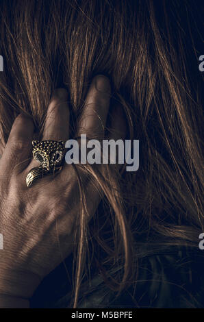 Die Frau mit den Fingern im Haar verfängt, das Tragen von Fox geformten Ring Stockfoto