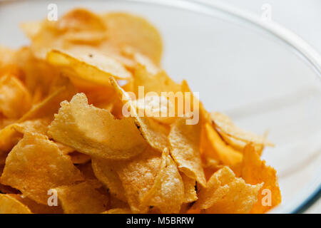 Chips in einem Glas Schale auf einem weißen Hintergrund Holz, schädliche Lebensmittel. Stockfoto