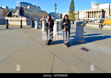 London, England, UK. Zwei muslimische Frauen mit Mobiltelefonen in Trafalgar Square Stockfoto