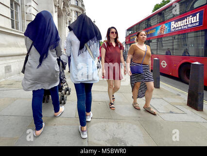 London, England, UK. Zwei junge muslimische Frauen Kopftücher vorbei gehen Frauen in westliche Kleidung in Whitehall Stockfoto