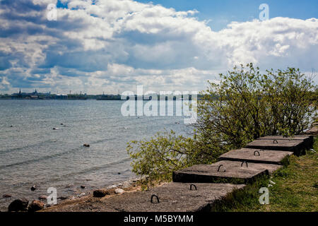 Tallinn Skyline von der Westseite des Hafen gesehen. Die konkreten Felsbrocken sagen, dass der Strand mehr Industrie als Freizeit. Stockfoto