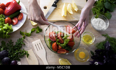 Weibliche Hand, denn Tomaten Stück mit holzlöffel von Glasplatte, Verlust Gewicht, Filmmaterial Stockfoto