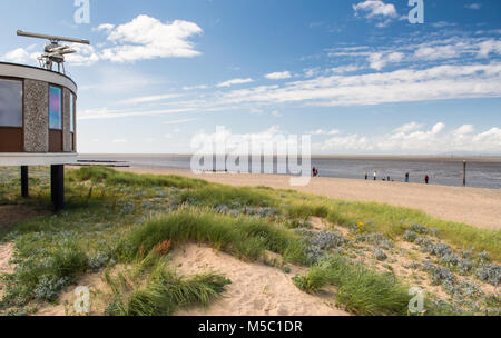 Die Menschen entlang der Sand von Fleetwood Beach in der Nähe von Blackpool, Lancashire, mit den Bergen des Lake District in die Distanz über Morecambe Stockfoto