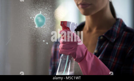 Frau meisterhaft kämpfen mit Flecken auf Glas, mit neuen Reinigungsmittel, Filmmaterial Stockfoto