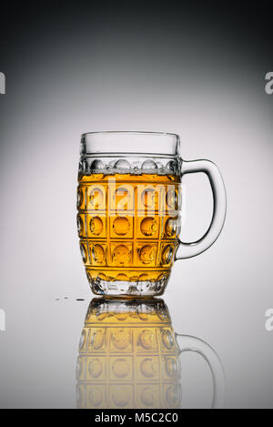 Glas mit Licht kaltes Bier in transparentem Glas auf Grau reflektierende Oberfläche Stockfoto