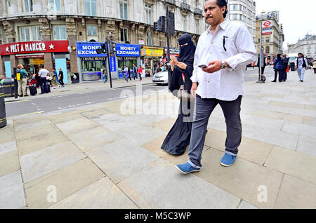 London, England, UK. Muslimische Frau mit ihrem Mann, auf Ihrem Mobiltelefon Stockfoto