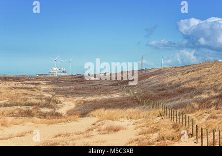 Die Dünenlandschaft in der Nähe von IJmuiden mit einem Kreuzfahrtschiff und Fabriken im Hintergrund Stockfoto