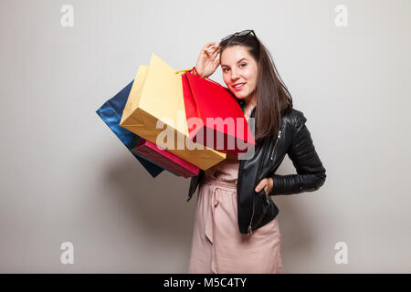 Pretty Woman in Lederjacke und rosa Kleid hält Taschen Stockfoto