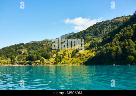 Schöne türkisblaue Wasser in der Nähe der Marmor Höhlen bei General Carrera See, Chile. Ein grüner Baum Hügel im Hintergrund und einem ruhigen blauen Himmel über. Stockfoto