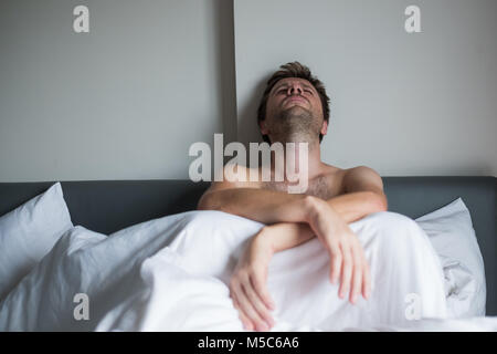 Porträt eines umgekippten junge Mann sitzt auf einem Bett allein. Stockfoto